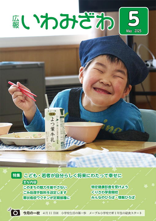 2025年4月11日(金曜日)、メープル小学校で新1年生の給食が始まり、満面の笑みで食べてるこどもの写真の広報いわみざわ2025年5月号表紙