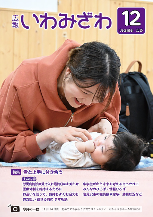 2025年11月14日(金曜日)、子育てのコミュニティ「おしゃべりルームばぶばぶ」で、あおむけで寝ている乳児とお母さんが手遊びしている写真の広報いわみざわ2025年12月号表紙