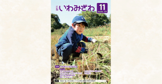 2026年9月25日(金曜日)に行われたメープル小学校と岩見沢小学校の合同稲刈りで、稲を刈る小学生の写真の広報いわみざわ2026年11月号表紙