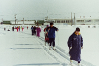 雪原の中でコース上に列になり歩くスキーをしている人の様子が写る、平成10年の歩くスキーの集いの写真