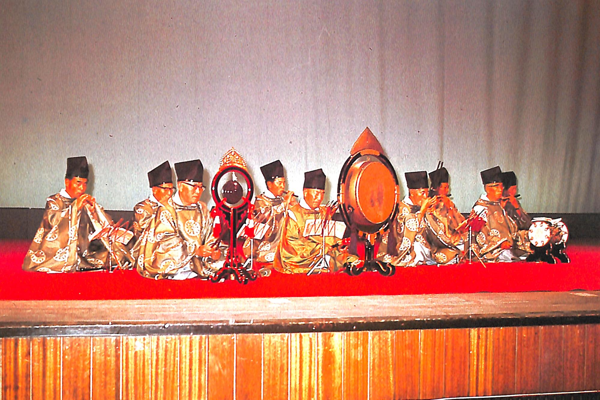 赤い絨毯の舞台の上で、着物を着て雅楽を演奏する岩見沢雅楽会の写真