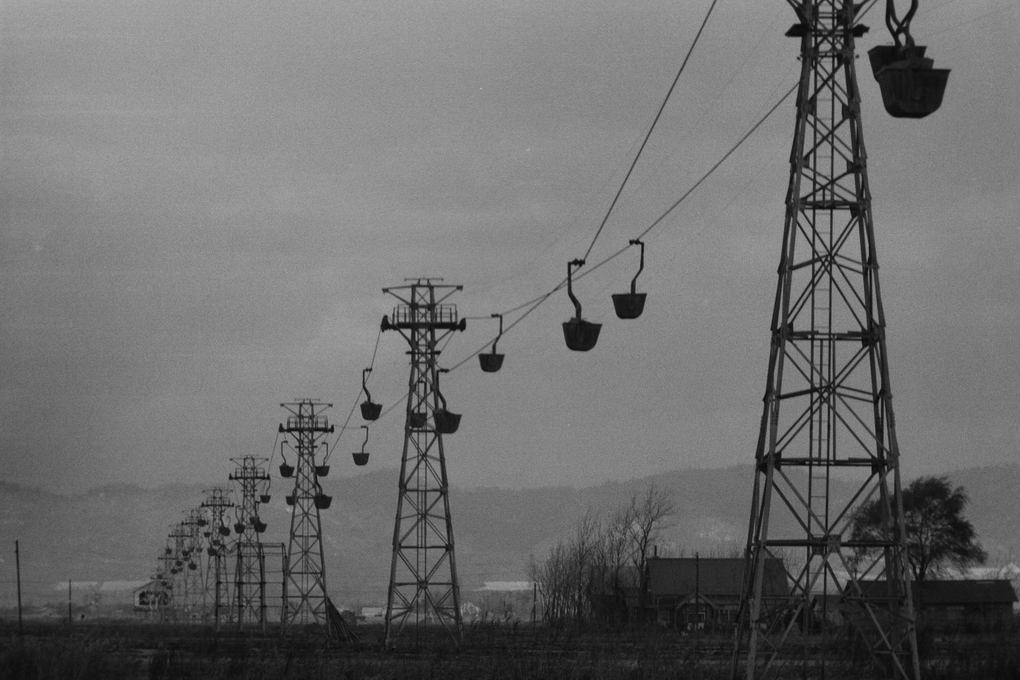 鉄塔が並び、ゴンドラで土を運ぶ様子が打つる昭和44年大願地区の索道客土の白黒写真