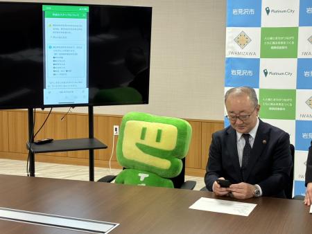 岩見沢市長がスマートフォンでe-Taxを模擬体験している写真