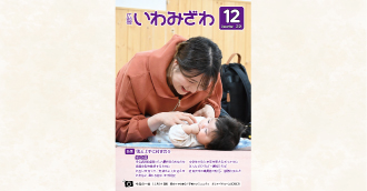 2025年11月14日(金曜日)、子育てのコミュニティ「おしゃべりルームばぶばぶ」で、あおむけで寝ている乳児とお母さんが手遊びしている写真の広報いわみざわ2025年12月号表紙