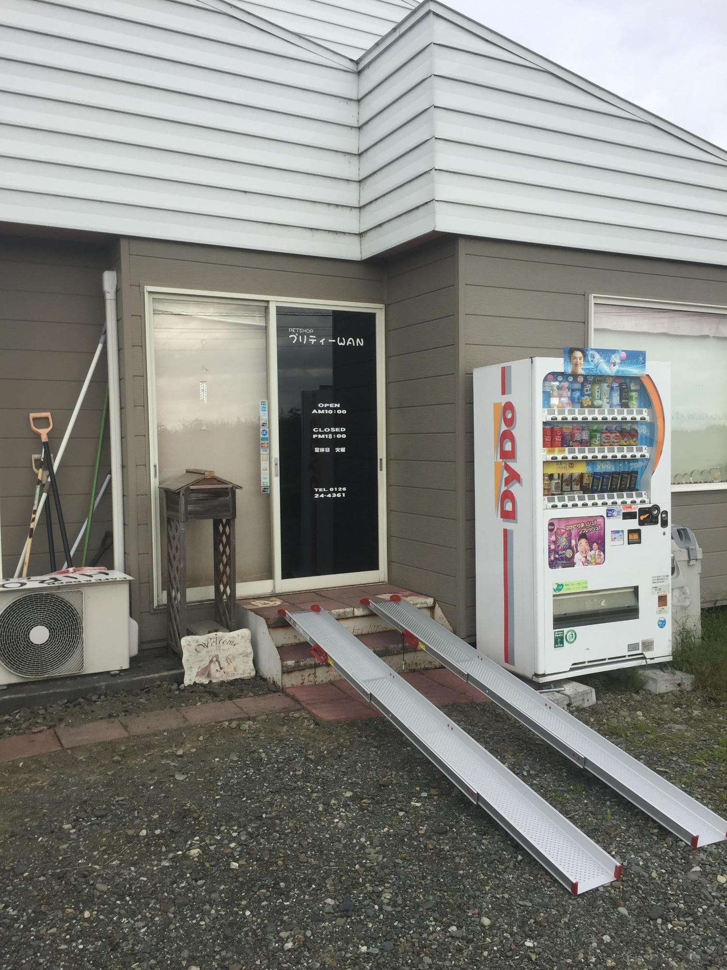 玉砂利の駐車場とスロープが設置された店舗入り口の写真