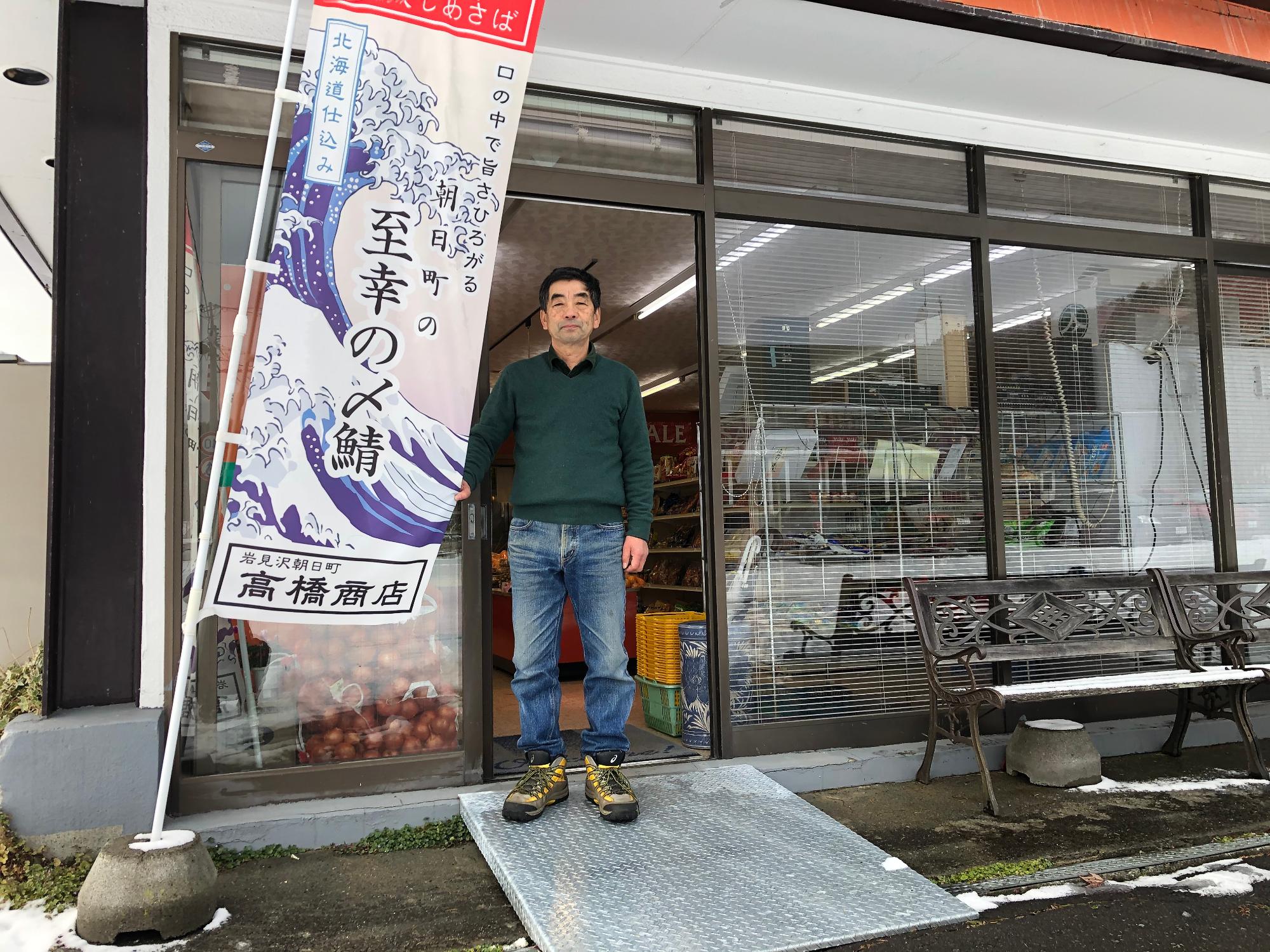 入り口に設置された新しいスロープの上に立ちほほ笑む店主の高橋さんの写真