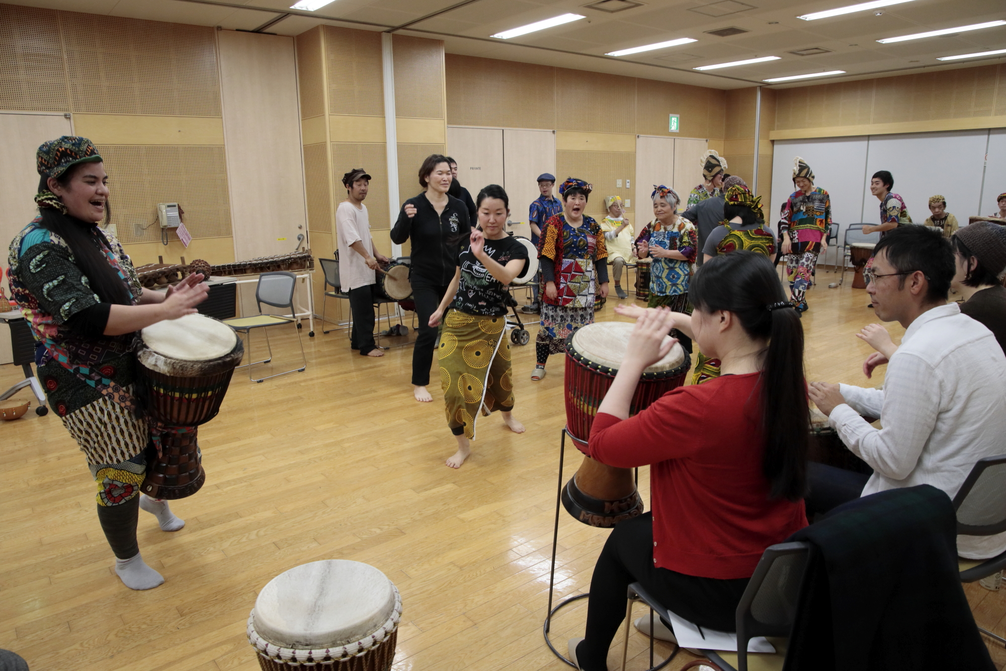 室内で民族衣装を身にまとい楽器を演奏する人たちや、それを椅子に座って見ている人たちの写真