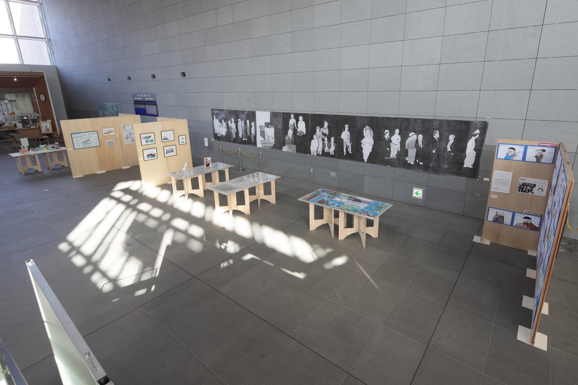 ロビーの壁や通路に写真や絵画等の様々な作品が並べられた展示会の写真