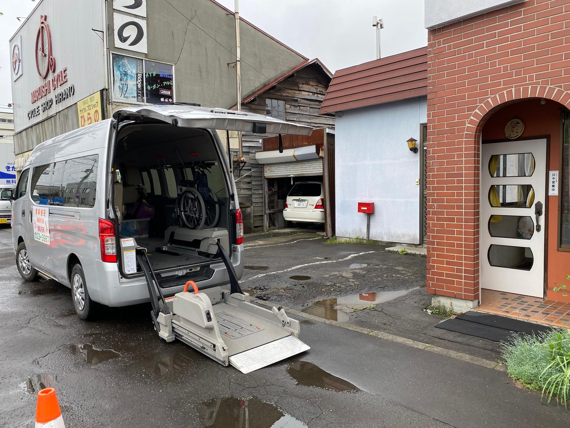 バックドアから機械でリフトを降ろしている様子の福祉車両の写真