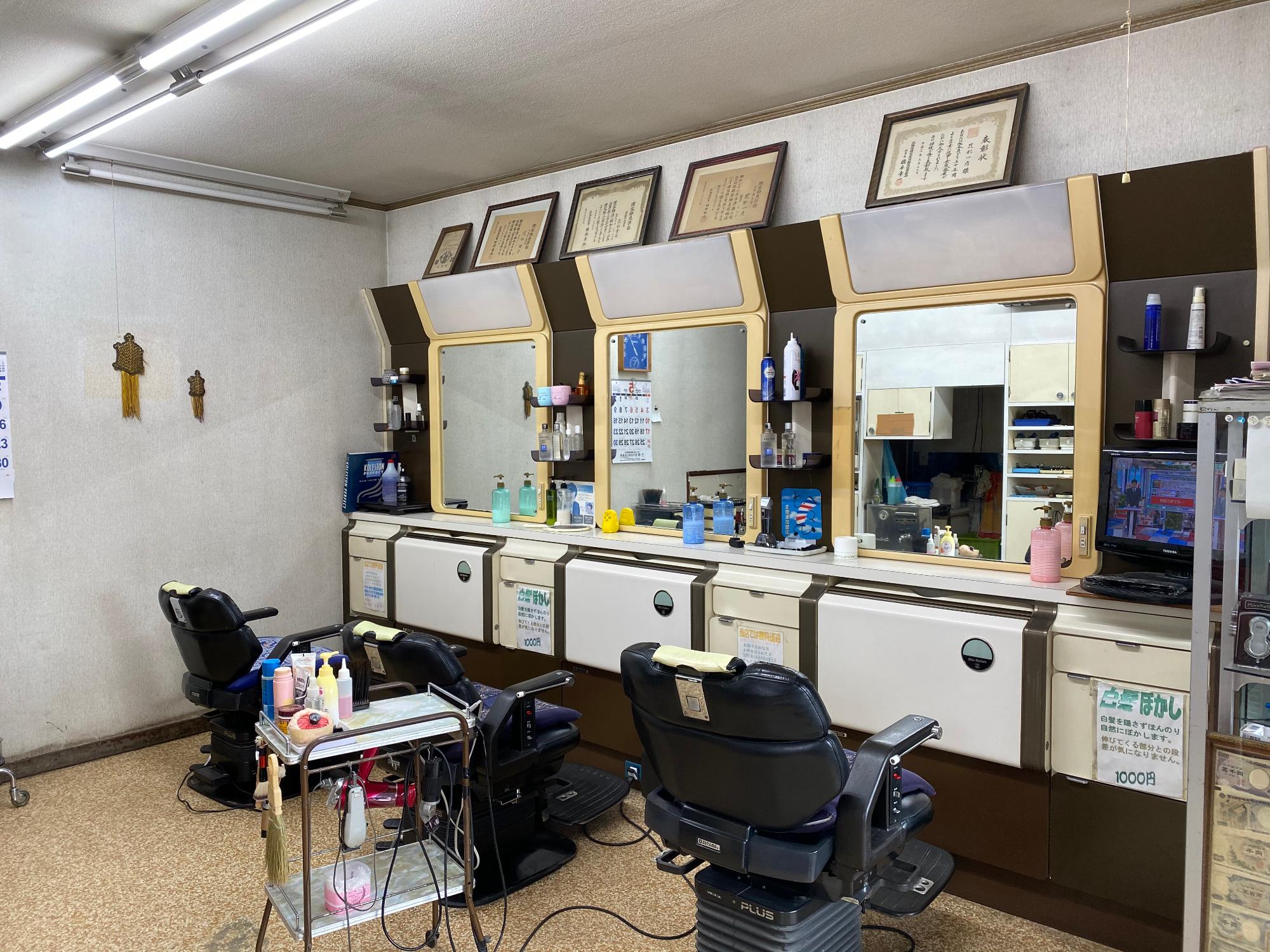 散髪用の機械や椅子が並ぶ店舗内観の写真