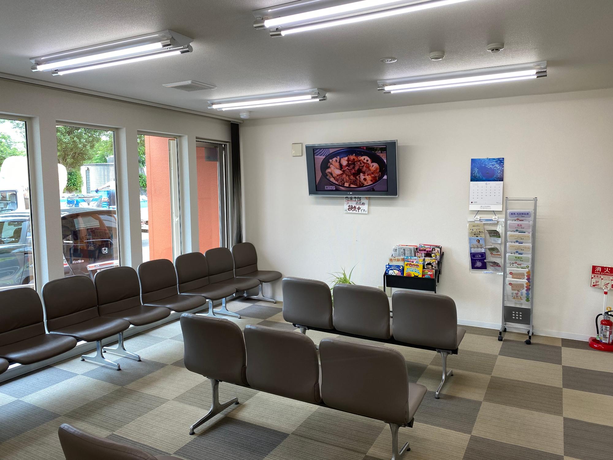 茶色い椅子が液晶テレビに向かって並べられている調剤薬局待合室の写真