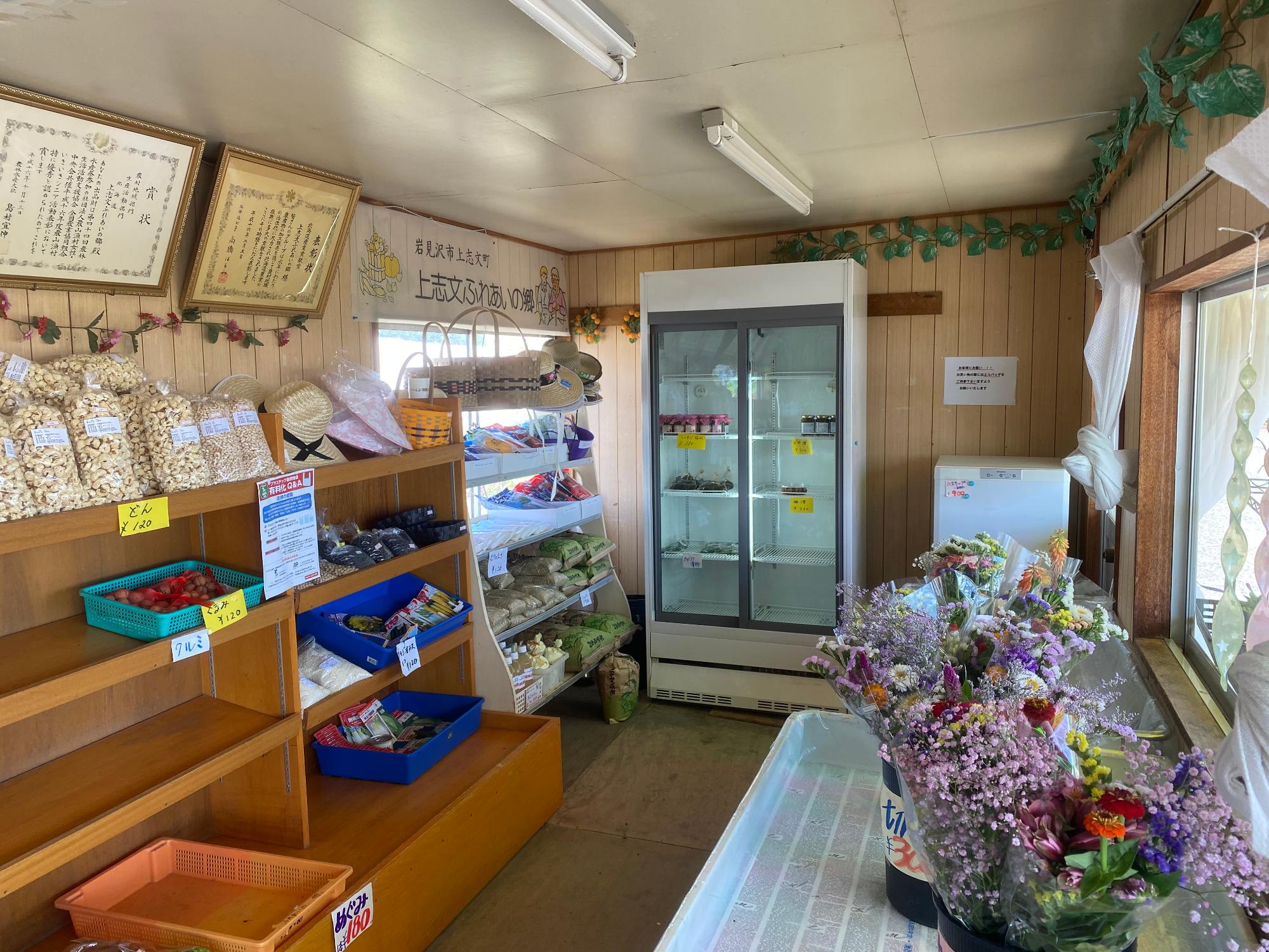 農産物やその加工食品と切り花が並べられている店内内観の写真