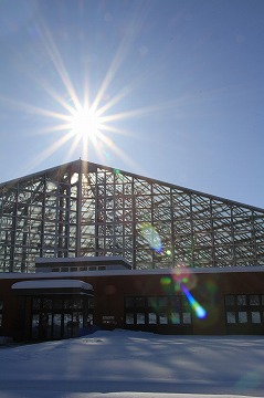 三角屋根の建物と太陽が写っている雪景色の写真