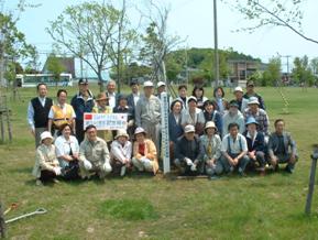 記念植樹の際に撮影された、樹木が並ぶ芝生での岩見沢日中友好協会の写真