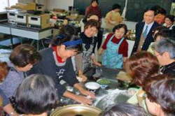 総領事夫人の水餃子づくりに見入っている市長や受講者たちの写真