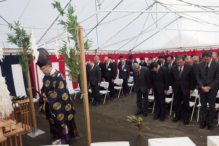 新庁舎改築工事安全祈願祭の様子を撮影をした写真。スーツを着た大勢の大人と、神社から来た人が儀式を行っている。