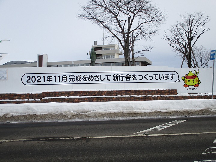 「2021年11月完成をめざして新庁舎をつくっています」と書かれた看板を撮影をした写真。