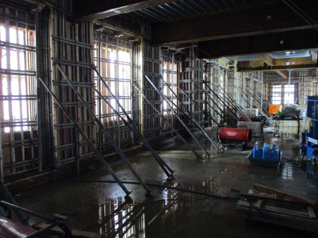 工事中の建物を屋内から撮影をした写真。屋内には工事に使用していると思われるたくさんの機材が置かれている。