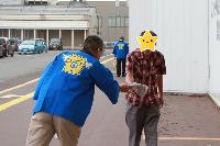 青いハッピを着た男性が選挙啓発物品を男性に渡している様子の写真