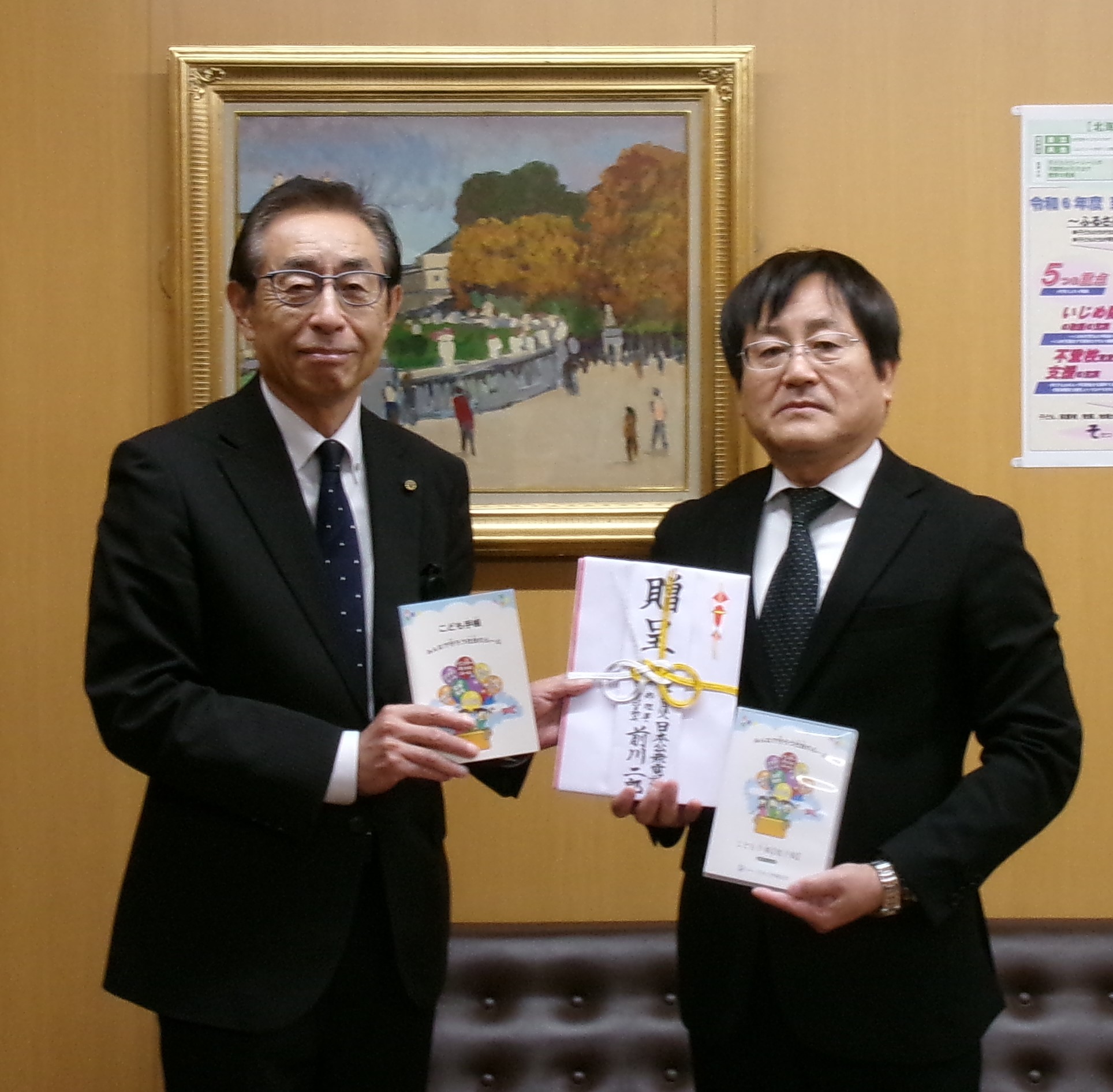 日本公衆電話会様(写真左側)から岩見沢市教育委員会教育長(写真右側)が「こども手帳」の寄付を受けました。