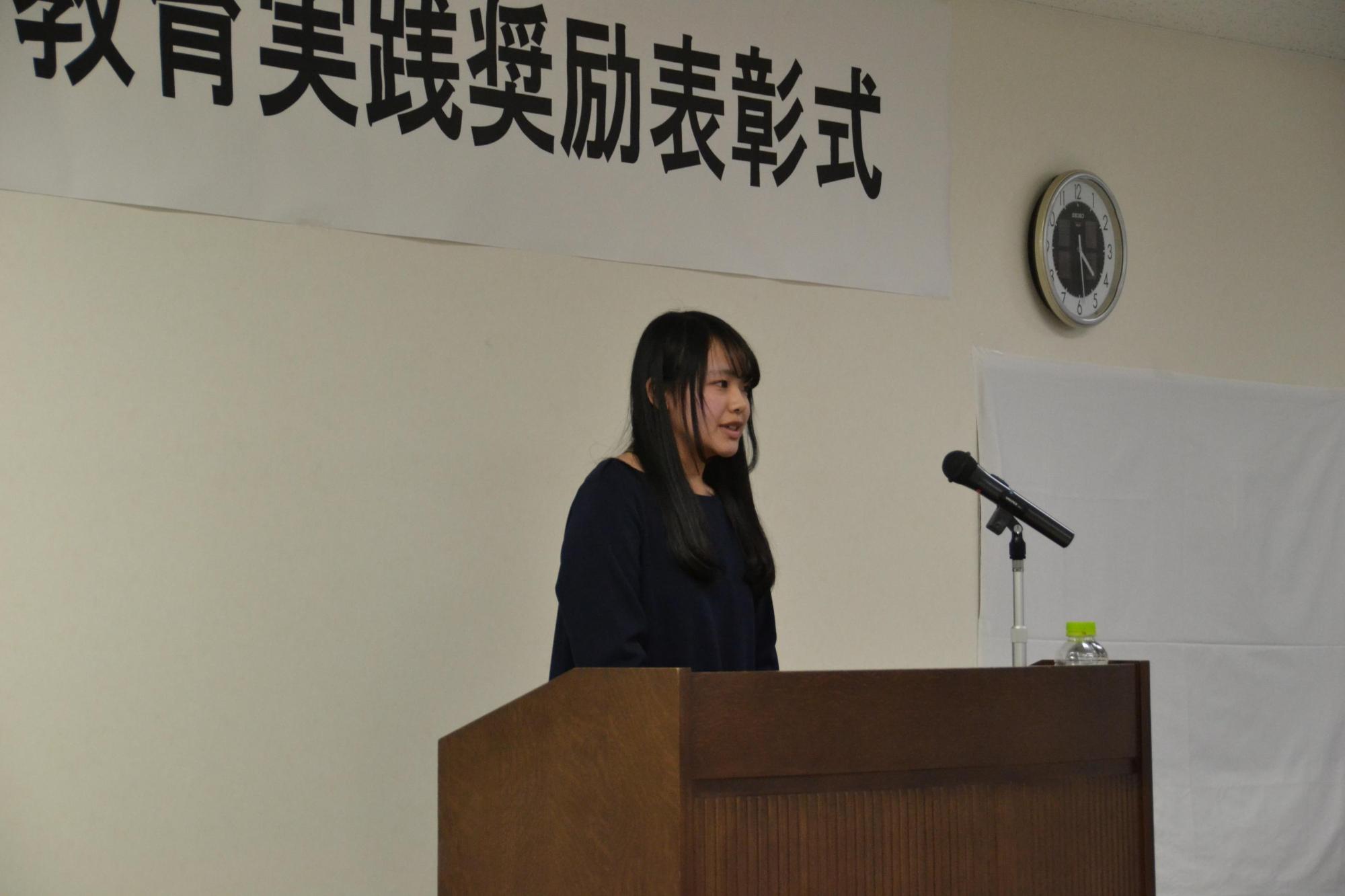 受賞者が演台の前に立ってスピーチしている写真