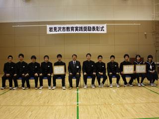 光陵中学校の団体受賞者の表彰式で椅子に座る数人の男女の様子の写真