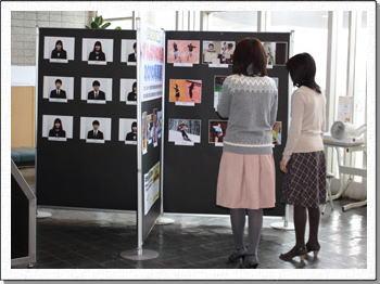 市役所の写真展示を見る二人の女性の写真