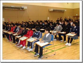 受賞者が椅子に座っている表彰式の様子の写真