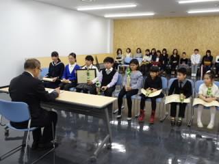 教育長と机を挟んで、8人の生徒が椅子に座っている様子