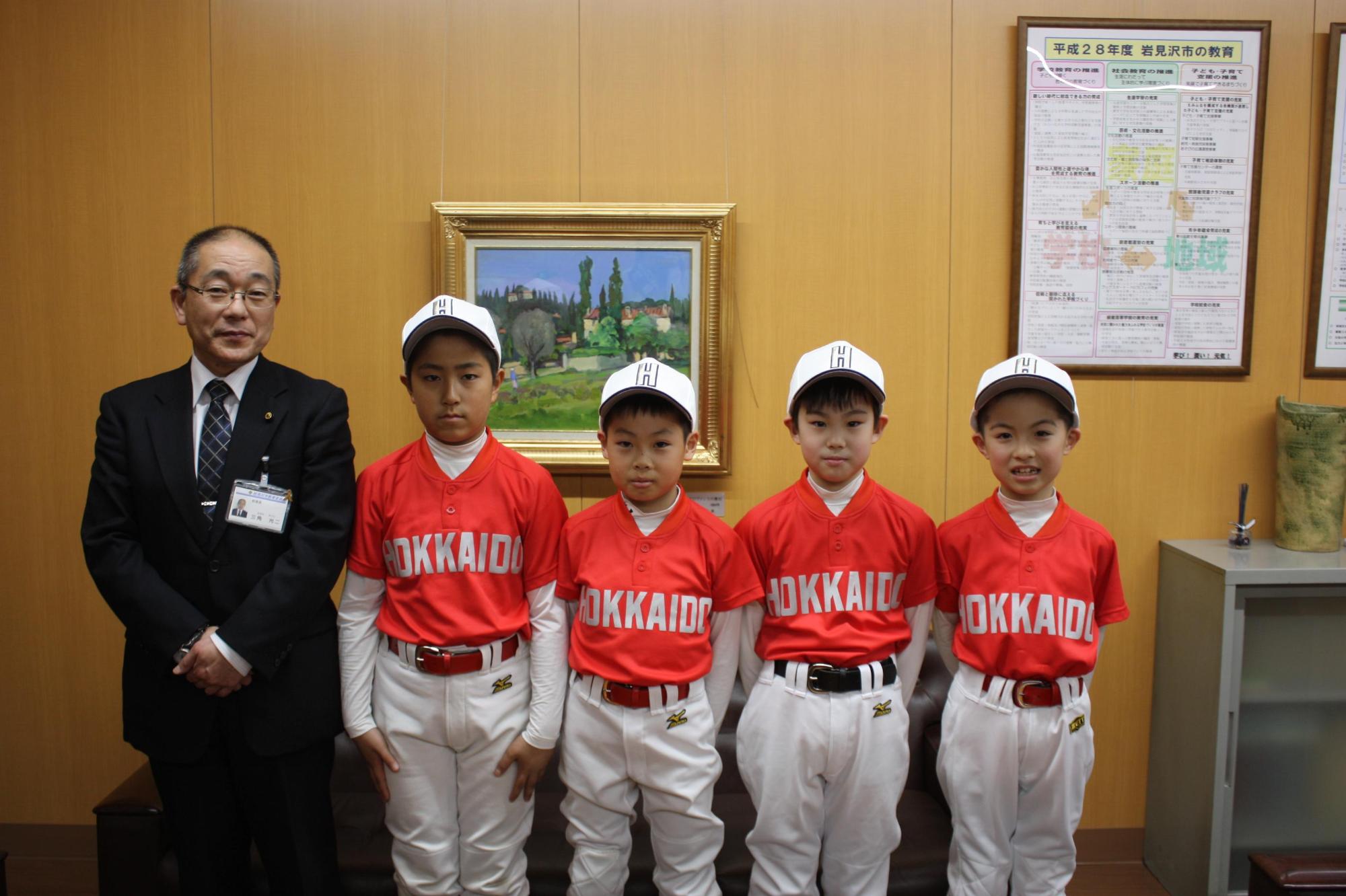 左から教育長、4人のユニフォーム姿の選手が並んでいる記念写真