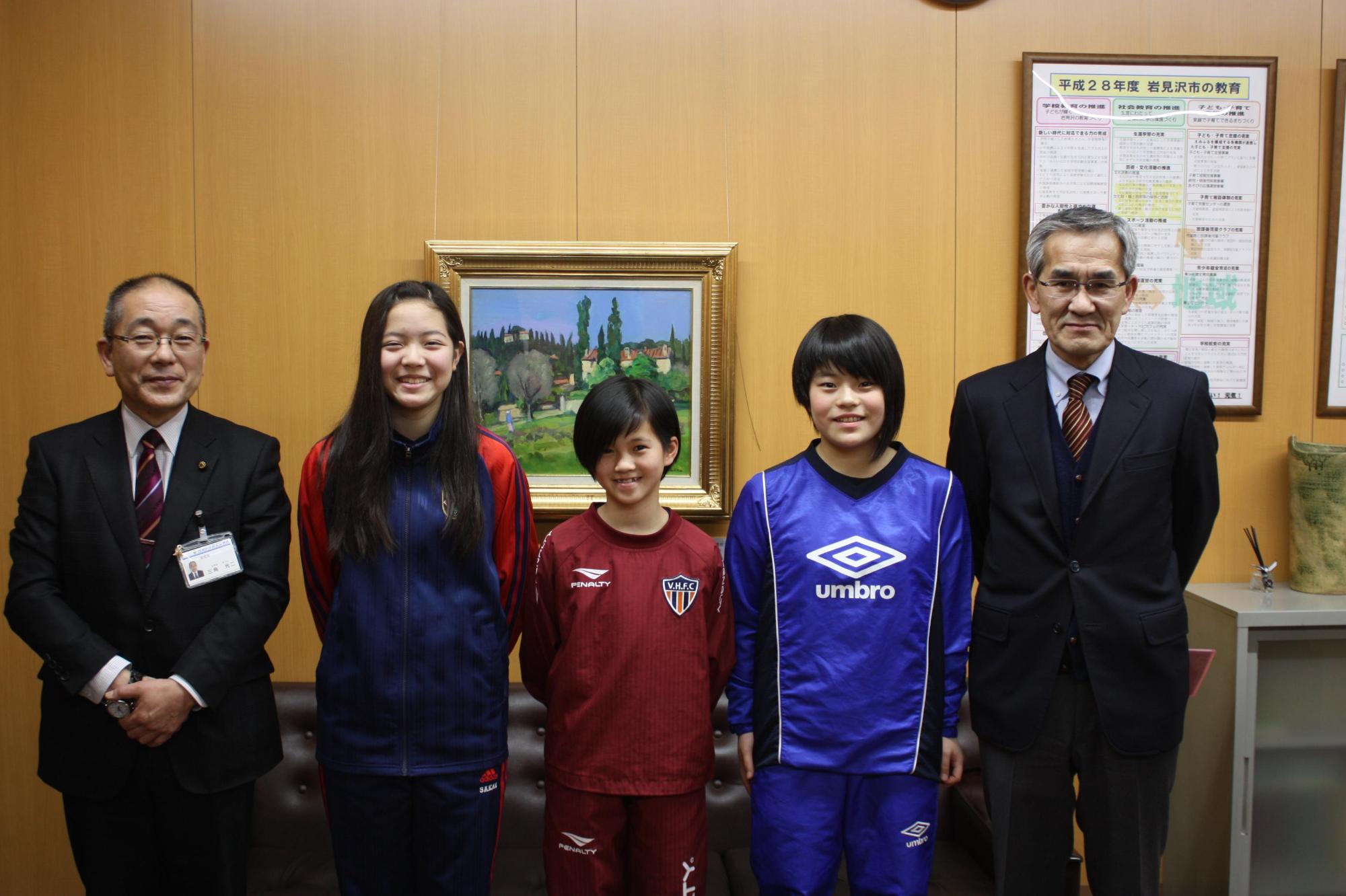 左から教育長、3人のユニフォーム姿の選手、1人の男性が並んでいる笑顔の記念写真