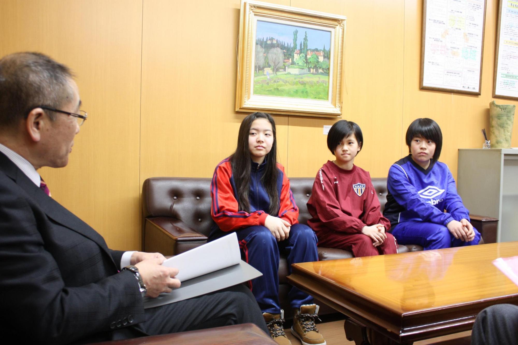 教育長とユニフォームを着た3人の選手たちが椅子に座り対話をしている様子