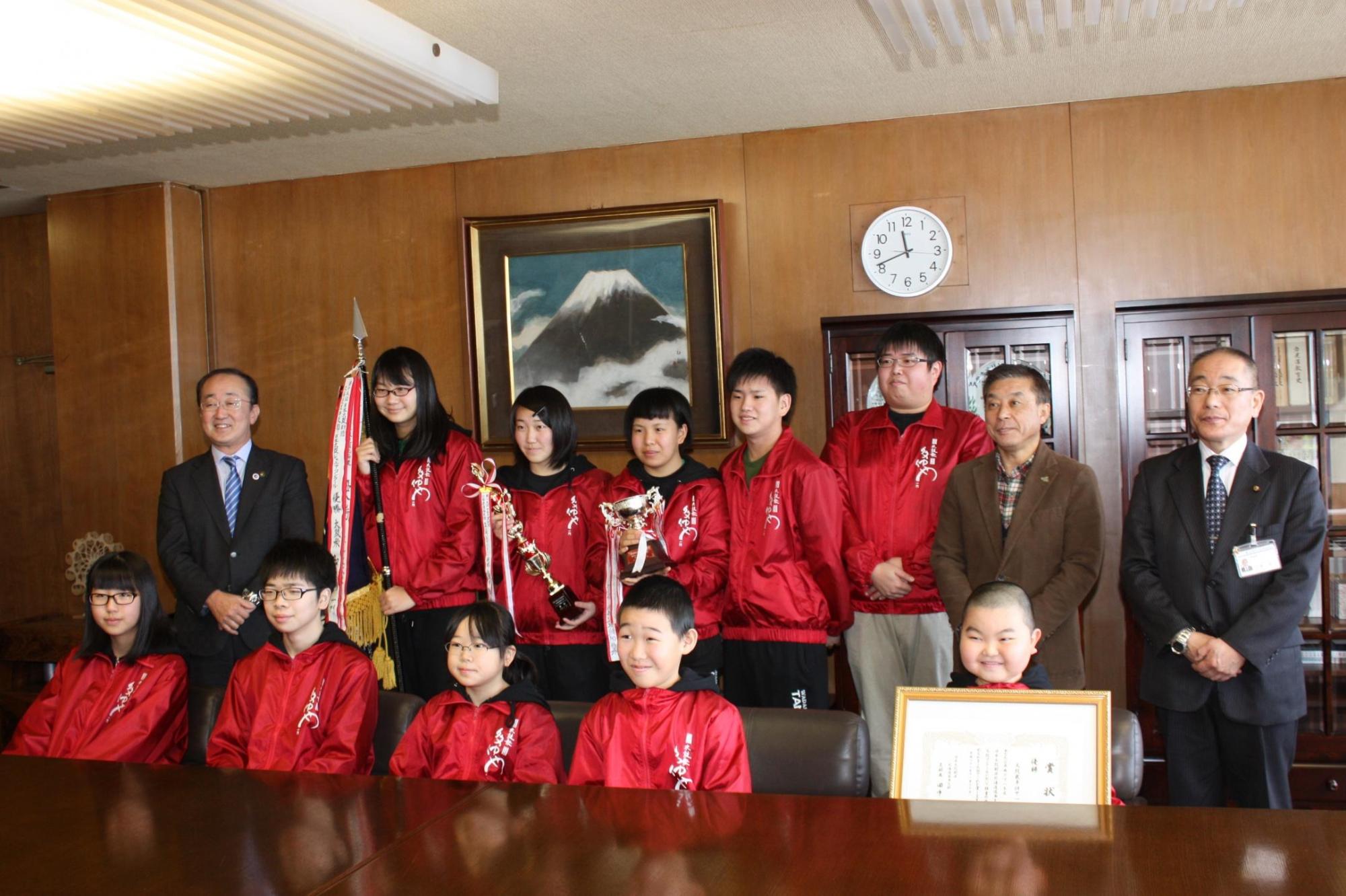 前列に5人、後列に7人並び、賞状とトロフィーを持っている太鼓衆多仲や一門のみなさんと教育長の記念写真