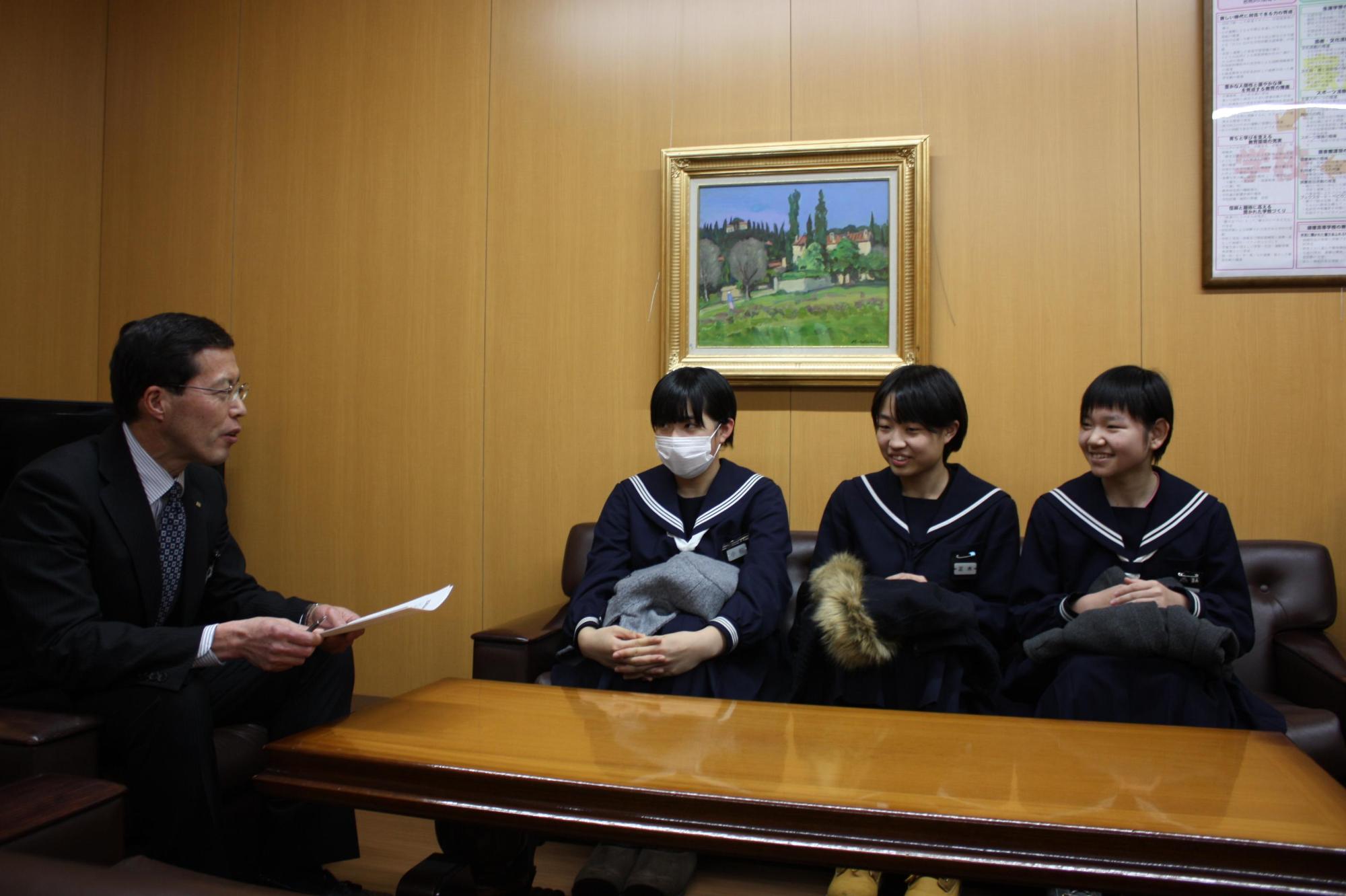 スーツを着た男性と北海道代表に選抜された3人の生徒が対話をする様子