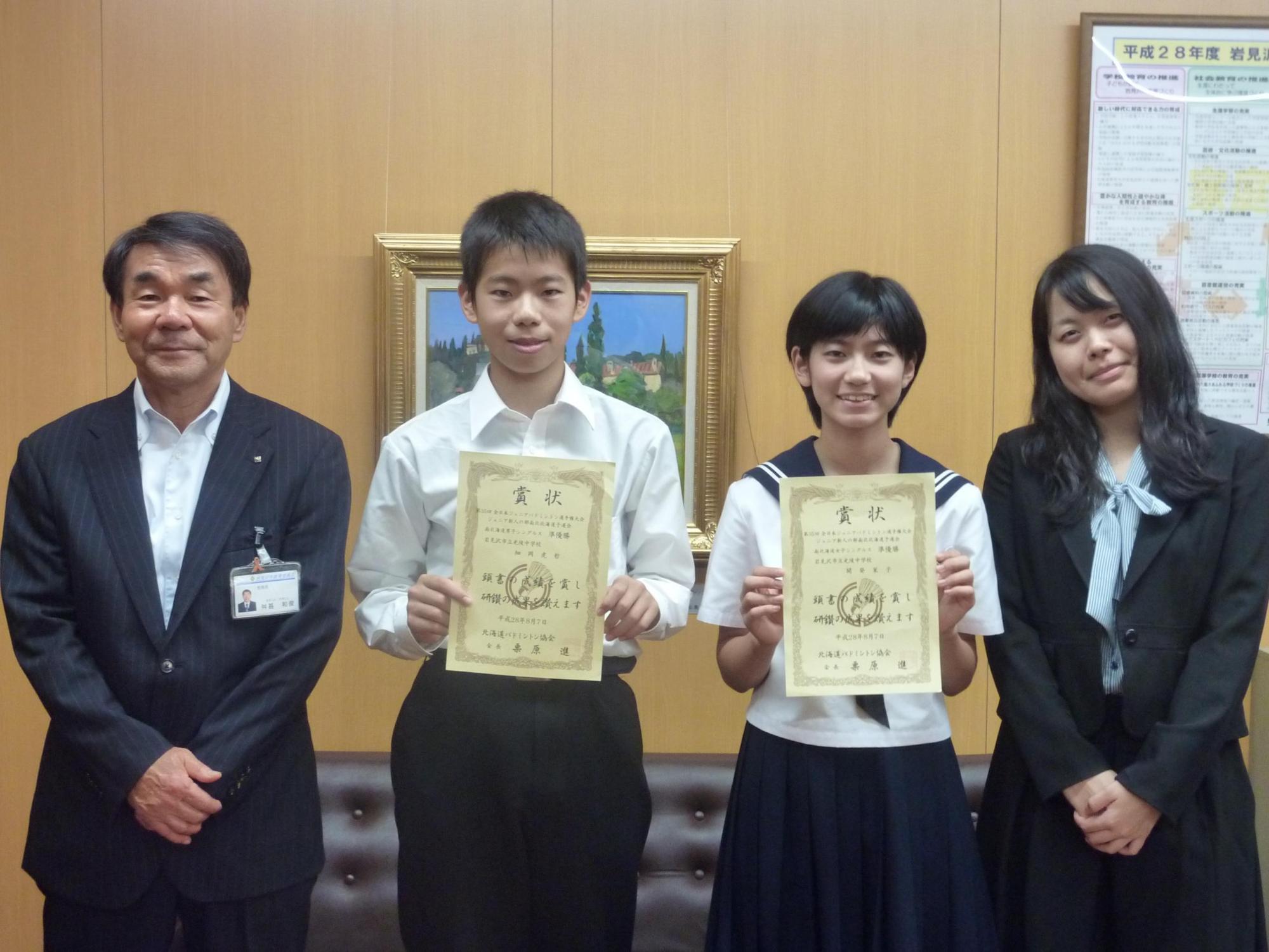 賞状を持つ細岡さんと開発さんを囲む教育長と女性の写真