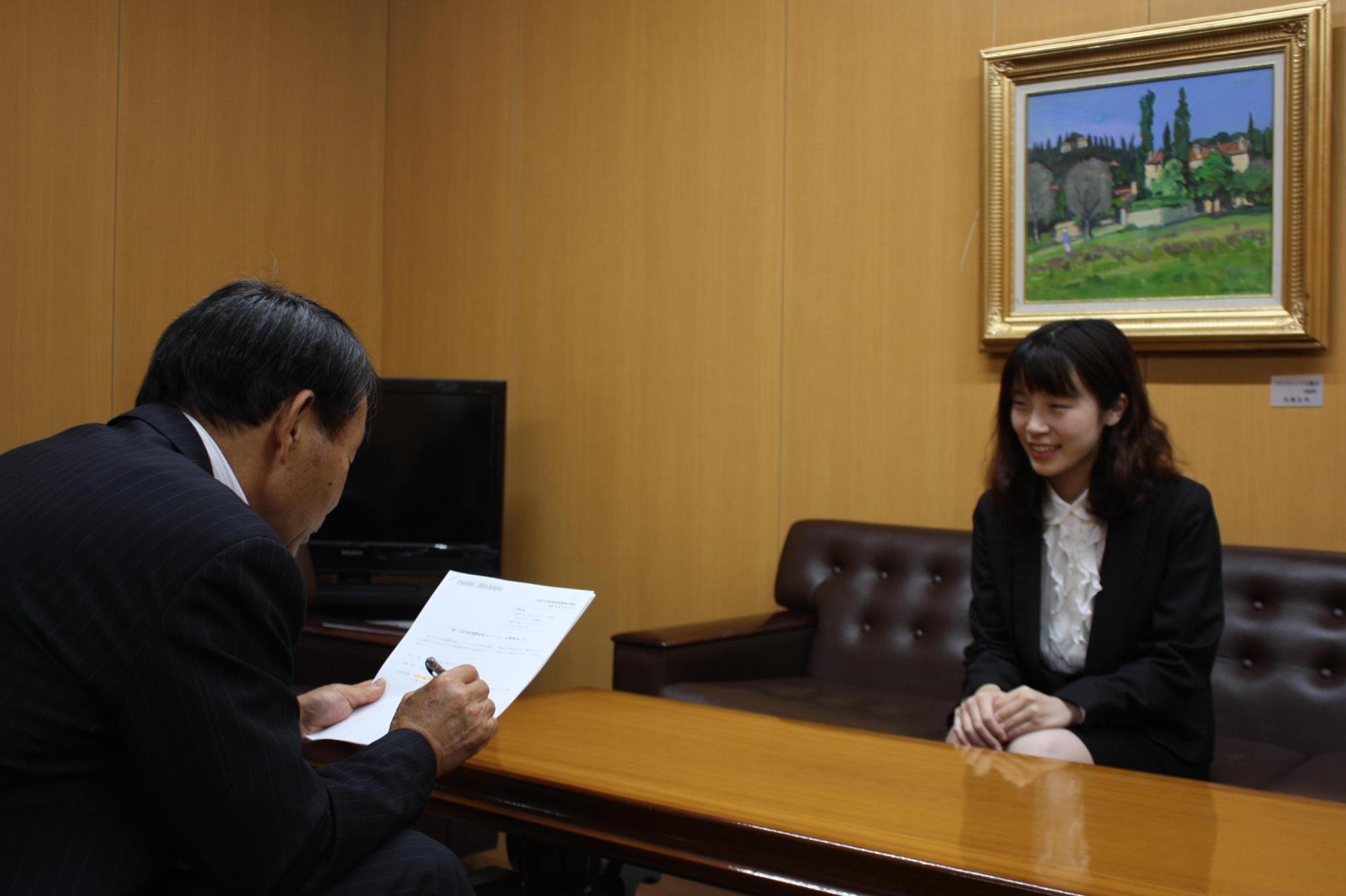 書類を眺める教育長と向かい合い笑顔の日向さんの写真