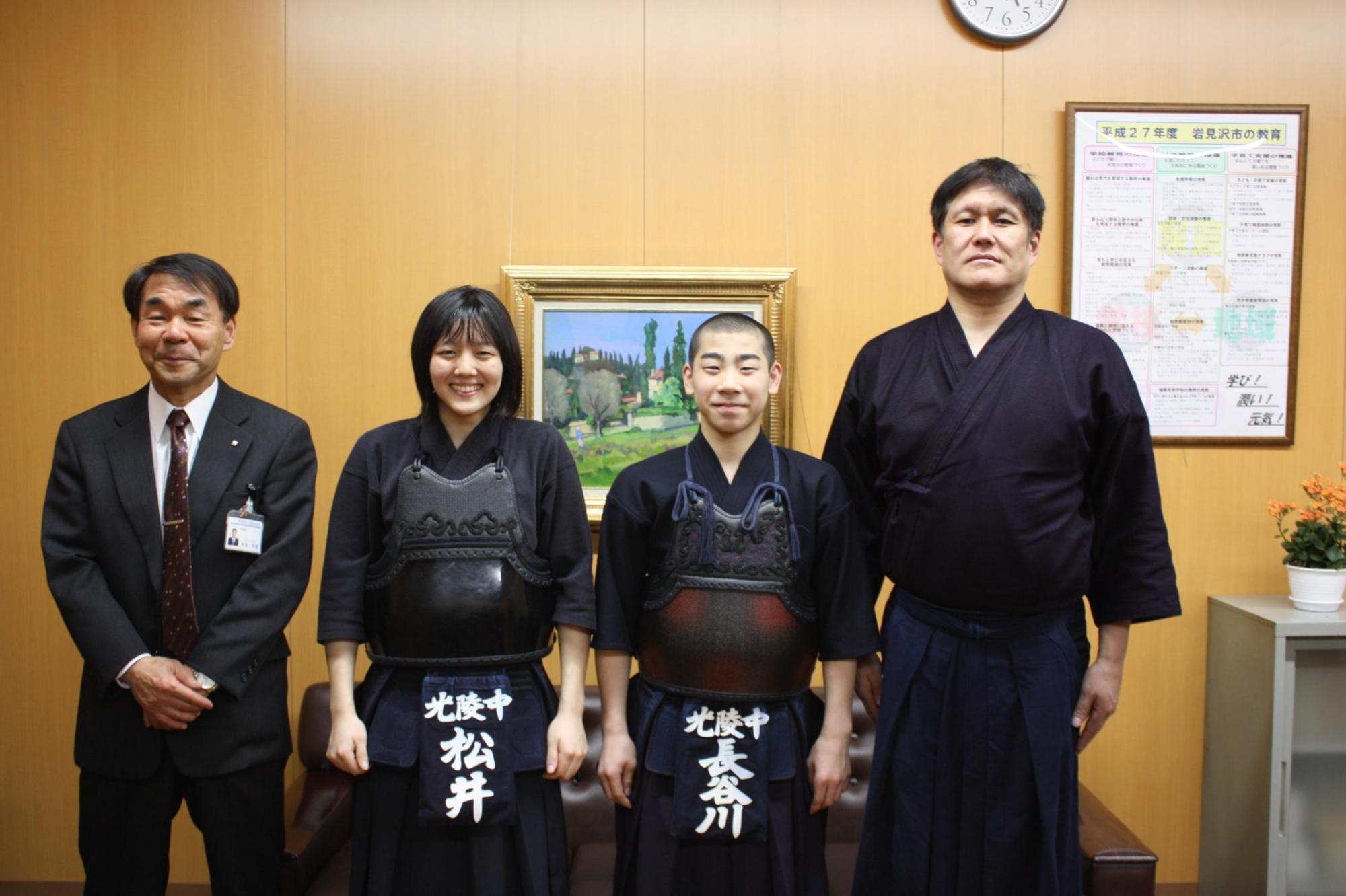 教育長と剣道着を着た二人の中学生と剣道着を着た大人が正面を向いて記念撮影をした写真。