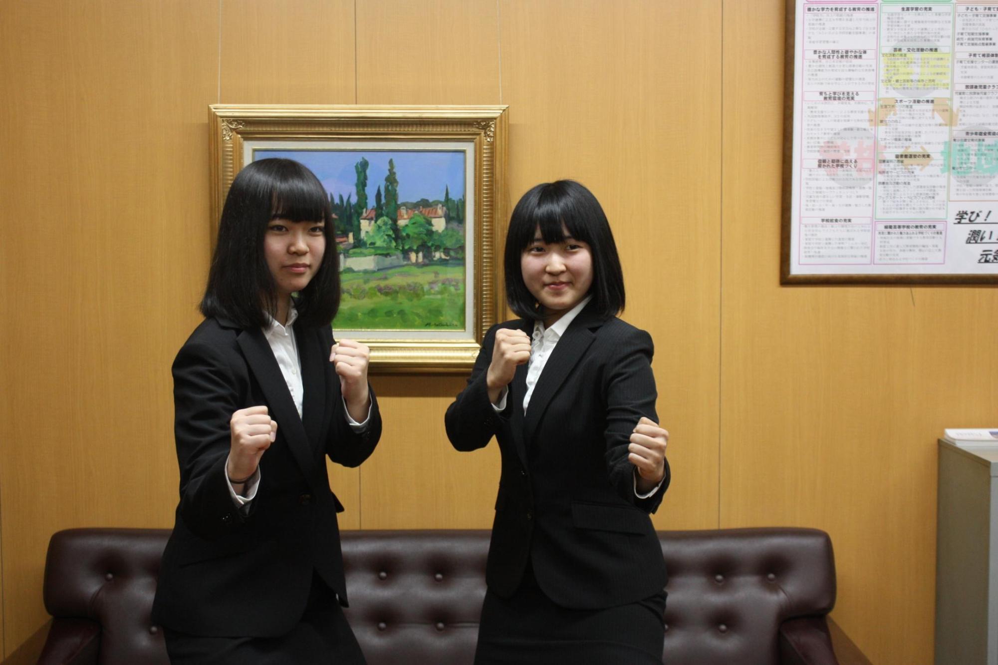 二人の若い女の子がガッツポーズをして記念撮影をした写真。
