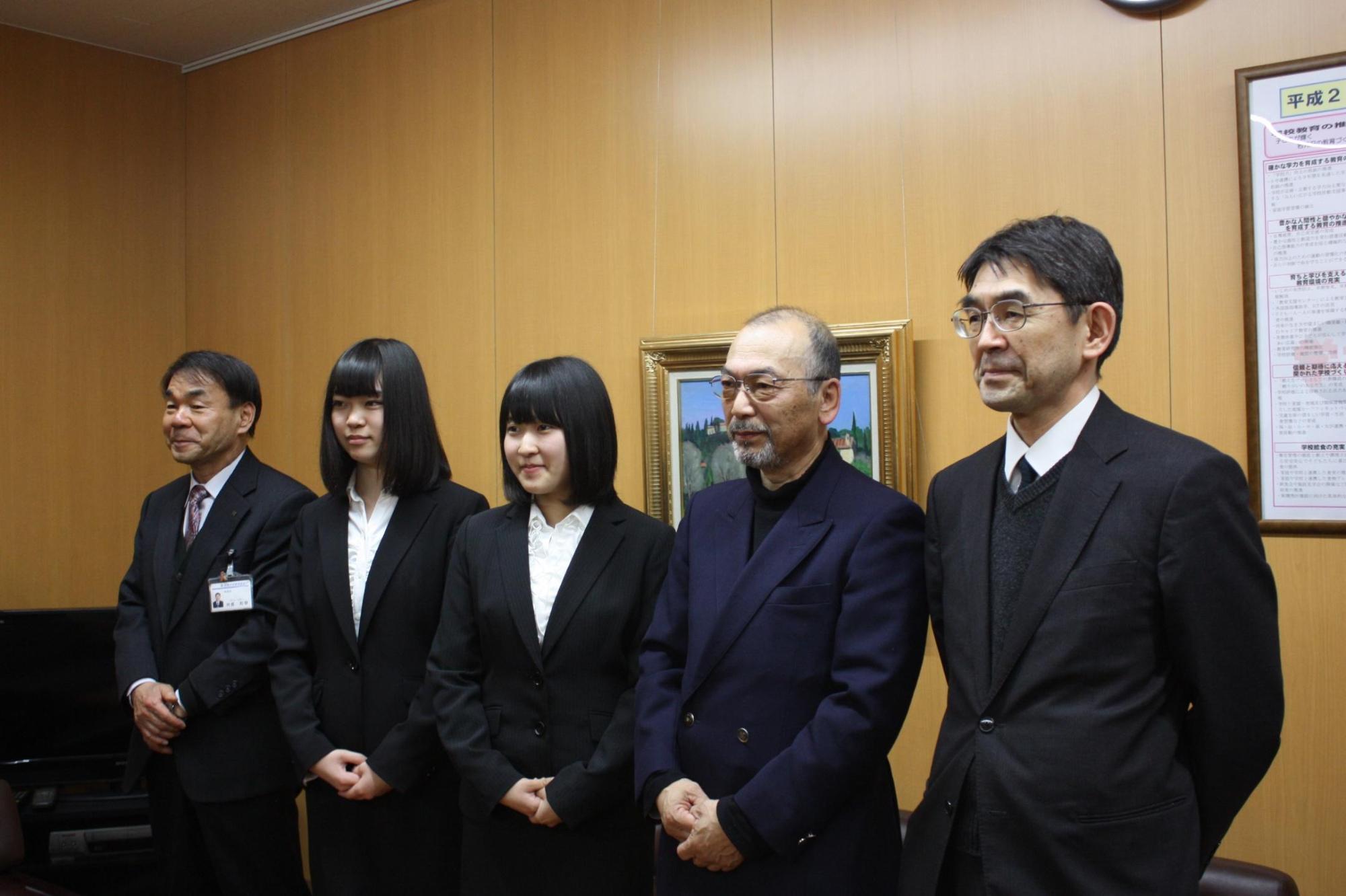教育長、二人の女の子、ジャケットを羽織った大人の男性、スーツを着た大人の男性が記念撮影をした写真。