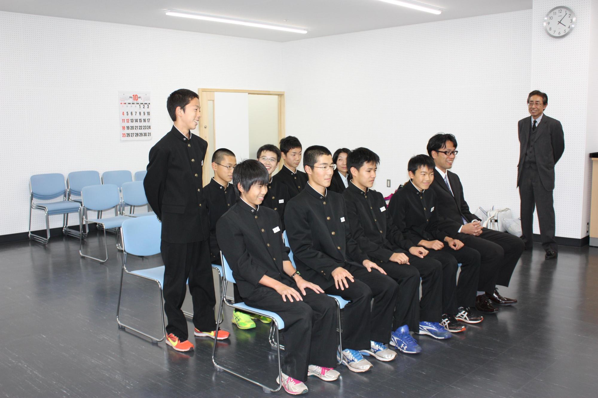 光陵中学校陸上部の皆さんが椅子に座っていて、一人の男子中学生が立って報告をしている様子の写真