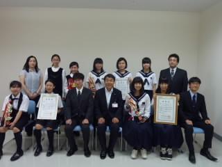 制服を着た学生数人と教育長が記念撮影をした写真。