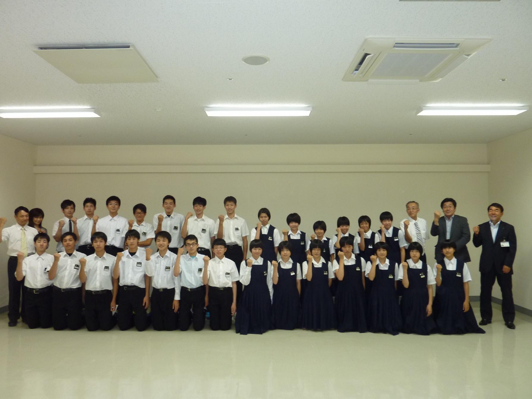 制服を着た子供数人、スーツを着た大人二人、教育長が記念撮影をした写真。