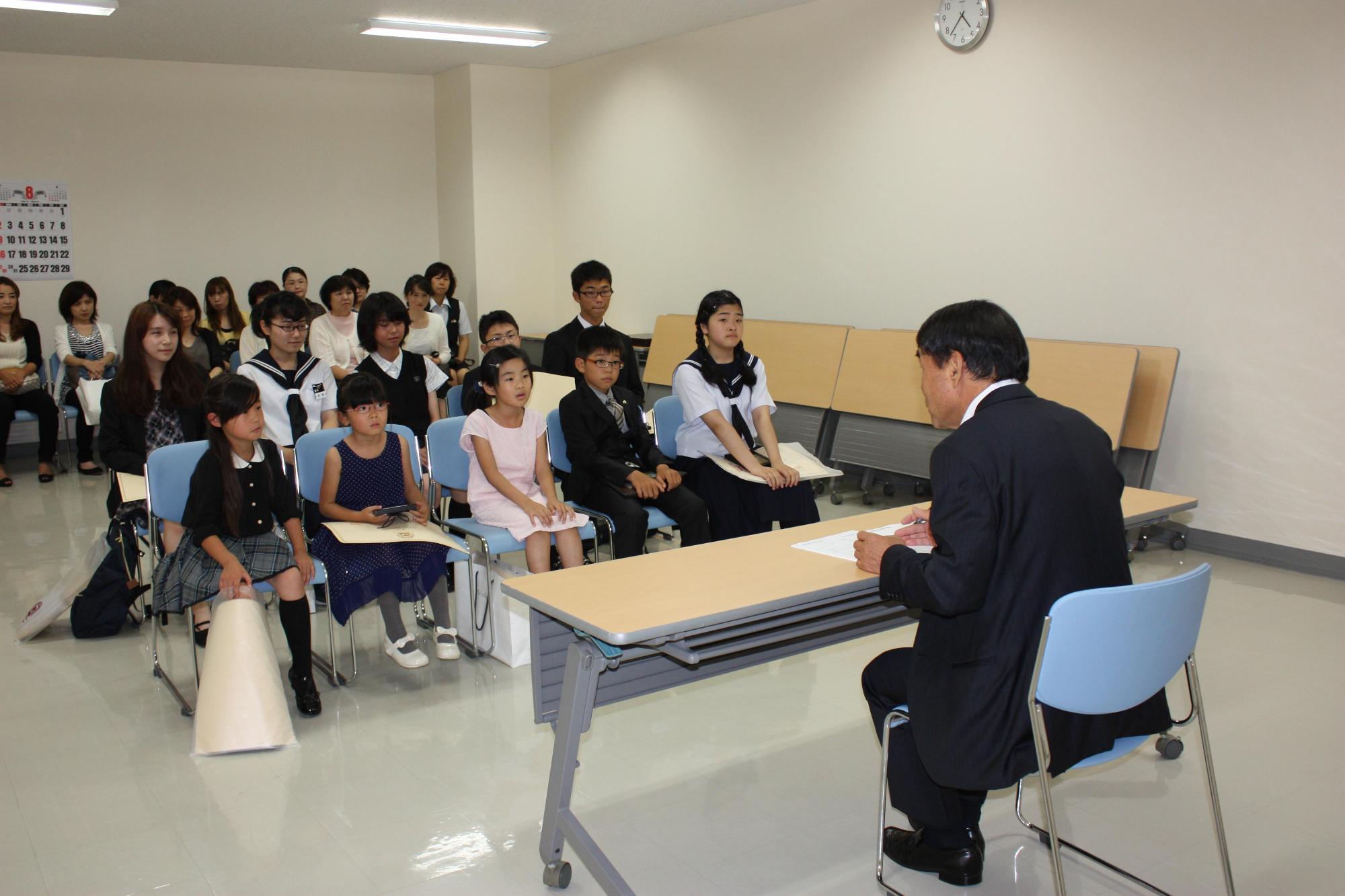 学生数人が、机を挟んで教育長の話を聞いている写真。