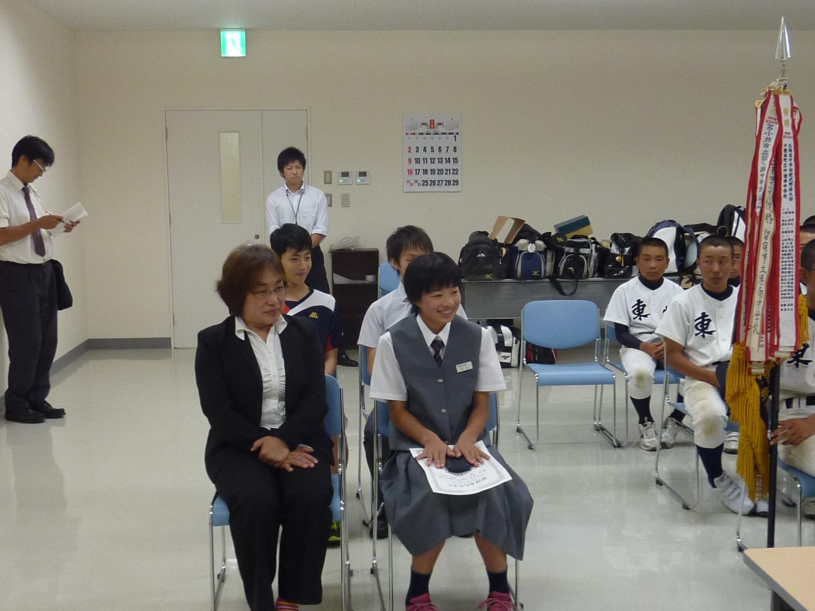 中山 璃子さんさんと制服を着た女の人は教育長の話を聞いている写真。
