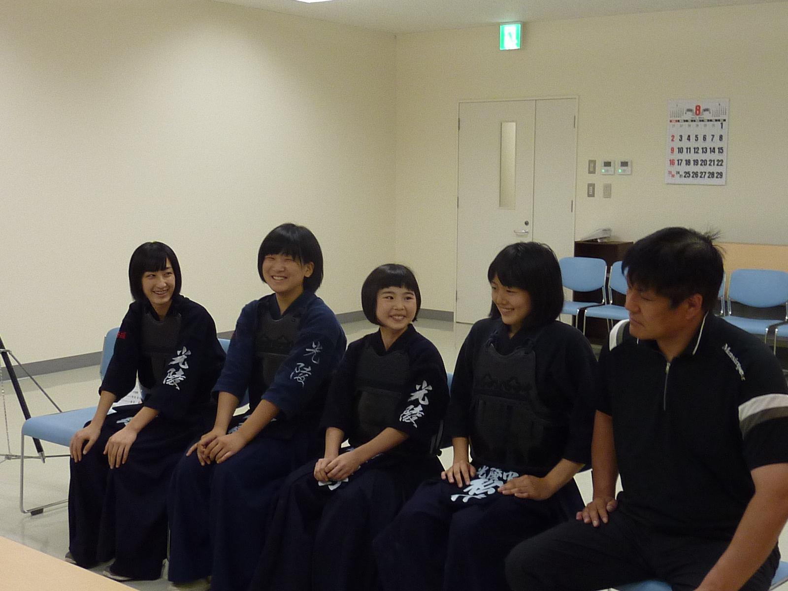 剣道着を着た中学生4人と男の人1人が談笑している様子を撮影した写真