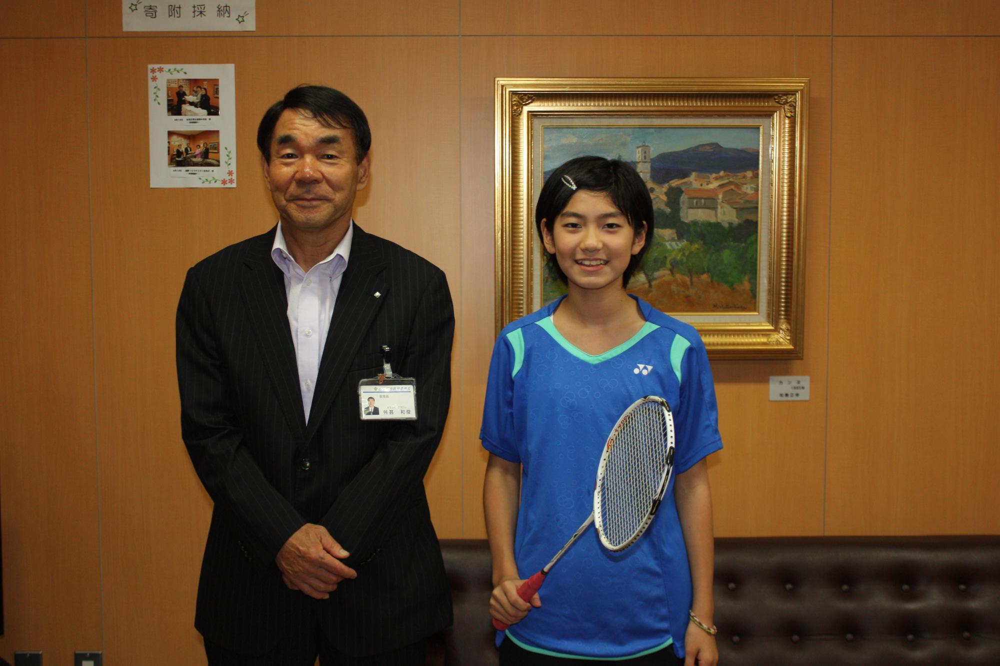 制服を着た開発さんと教育長が記念撮影をした写真。