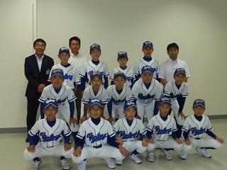 野球のユニフォームを着た子供数人と教育長が記念撮影をした写真。
