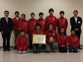 学生数人、男の人1人と教育長が記念撮影をした写真。