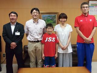 右から、赤い服を着た男性と、白い服を着た女性と、赤い服を着た生徒と、白いシャツを着た男性と、スーツを着た男性が並んでいる写真