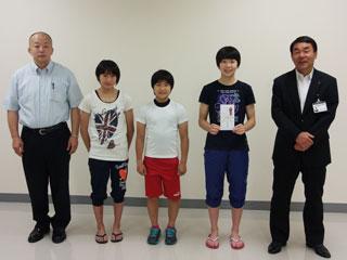 右から、スーツを着た男性と、3人の生徒と、薄い青色のシャツを着ている男性が並んでいる写真